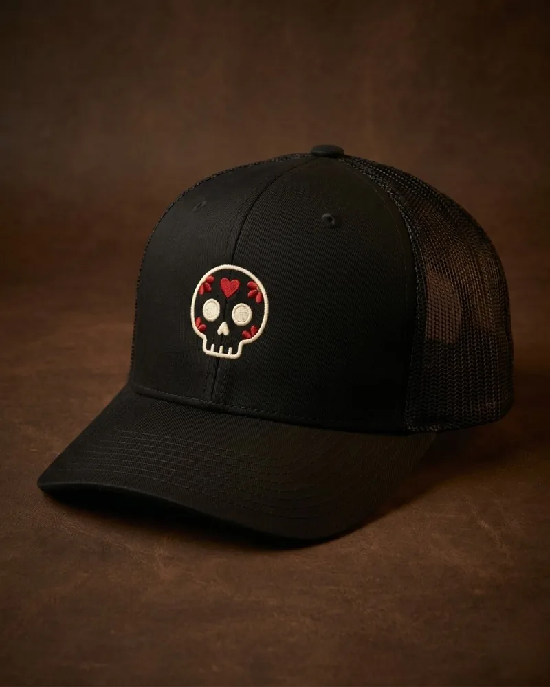 Gorra negra trucker con calavera Día de Muertos bordada en hilo crema con acentos rojos